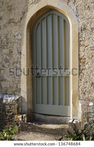 Painted wooden door in stonework wall with worn steps. Wiltshire. England
