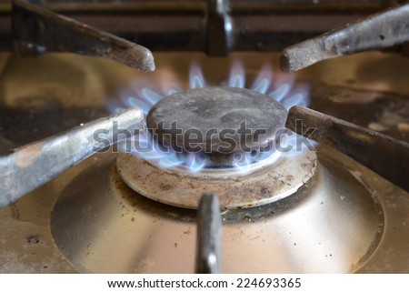 Blue flame on a domestic gas cooker ring. Dirty with food splashes.