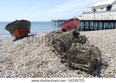 Lobster pots and fishing boats on shingle beach by the pier at Bognor Regis. West Sussex. England
