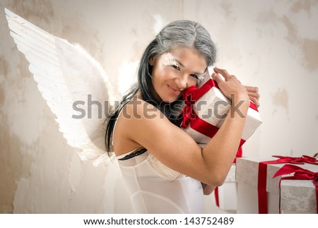 Young woman as angel with heap of gift boxes