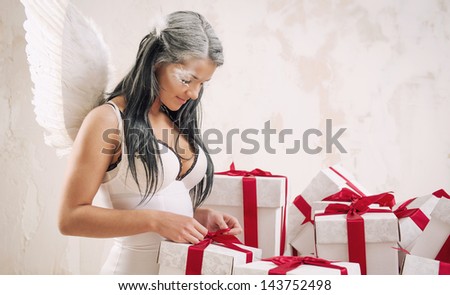 Young woman as angel with heap of gift boxes