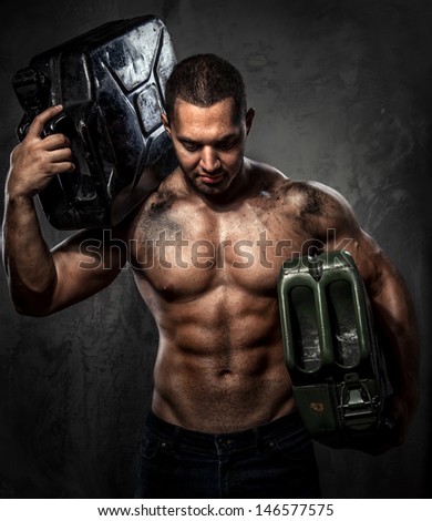 Muscular man with two metal fuel cans indoors