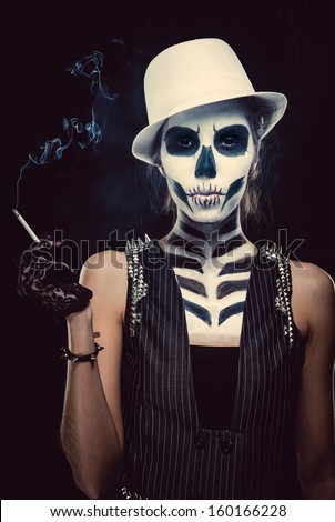 Woman with skeleton face art smoking over black background, conceptual photo