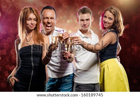 Cheerful group of young people with glasses of sparkling champagne over abstract background