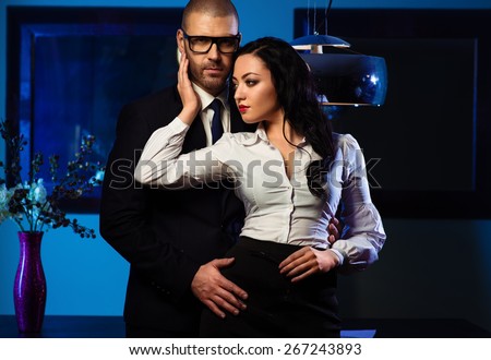 Couple indoors. Sensual brunette and handsome businessman hugging indoors. Office romance concept