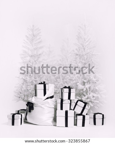Christmas trees with bag and heap of gift boxes. Studio shot, black and white image