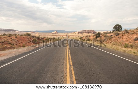 Country Highway with Straight road and dramatic sky . Shallow depth of field. A very Long road to Monument Valley