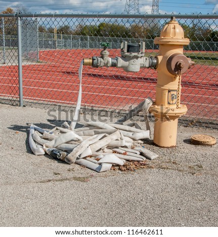 Hydrant with water hose by take and field and football stadium. Fire safety.