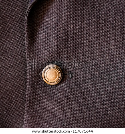 Close up of a Golden button on nice silky business suit coat. High Contrast. Corporate background. Business Background.