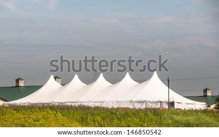 Party Tent or a big white banquet wedding tent for ceremonies. White tent against blue sky.