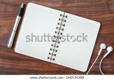 open diary, a pen and headphone on a wooden table. Study and journal concept