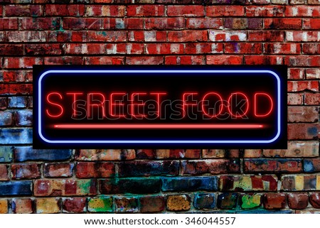 Street Food Neon sign on a Graffiti. Bricks wall
