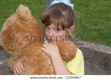 Offended child embraces her toy bear. The girl looks tragic and firmly presses for a toy.