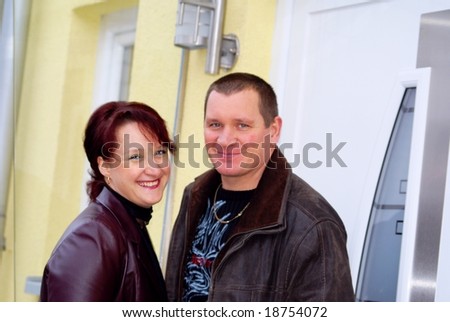 Young Couple thirty forty years, is near the facade of private homes and nice, happy smile.