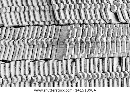 The black and white background image of the pile of the old clay roof tiles