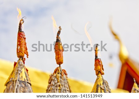 The worm\'s eye view closeup image of three yellow and red candles in a temple