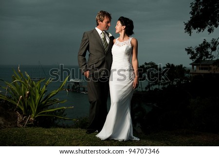 Bride and Groom looking at one another, standing on a hill with water in the background
