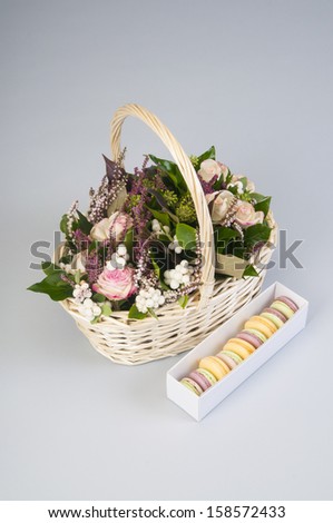 Basket with roses and french macaroons on gray background