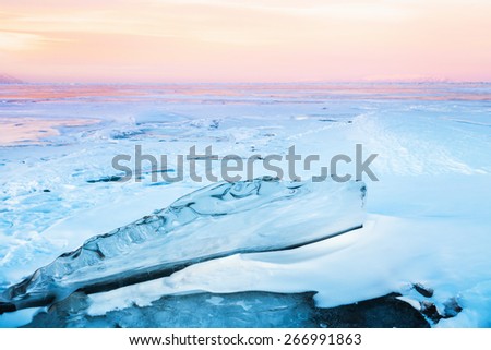 Transparent block of ice under sunset sky. Baikal lake, Russia