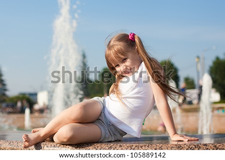 Charming girl sitting by the fountain
