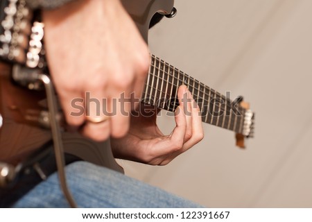 The hand on the strings of electric guitar