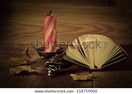 Candle and book on a wooden table in dark colors