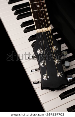 Fragment of a guitar lying on piano keys