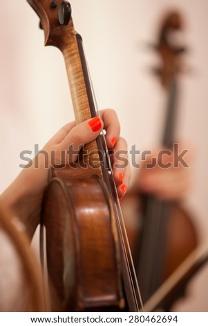 The hand of the girl holding the violin in the orchestra closeup