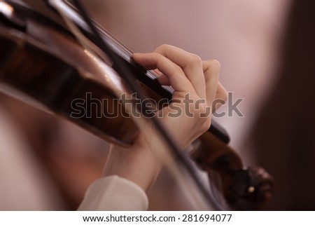 The hand of the girl playing the violin in dark colors