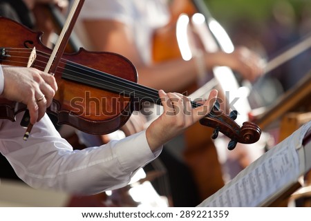 Violin in the hands of a musician in the orchestra closeup