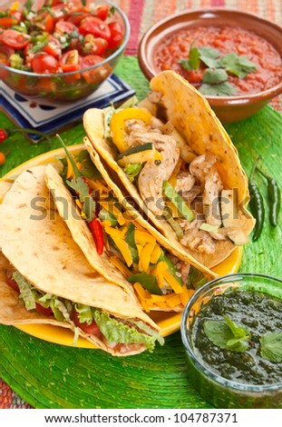 Colorful Traditional Mexican food dishes: various fajitas, salsa verde, tomato salsa, salsa cruda served on a beautifully decorated table