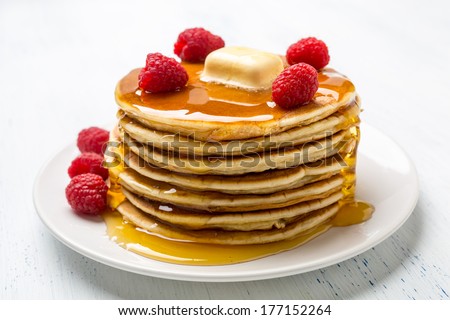 Big Pile Of American Pancakes With Raspberries, Melted Butter And Maple Syrup
