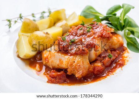 Plate of Cod or Pollack  Fish Fillet Stewed in Tomato and Thyme Sauce Garnished with Boiled New Potatoes