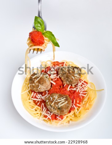 one serving of spaghetti with meatballs in tomato sauce and some spaghetti with sauce and basil on a fork