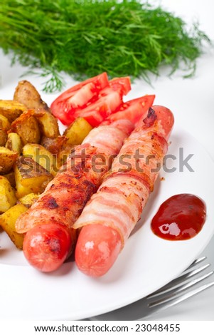sausages wrapped in bacon, roasted potatoes, sliced tomatoes and ketchup on a white plate