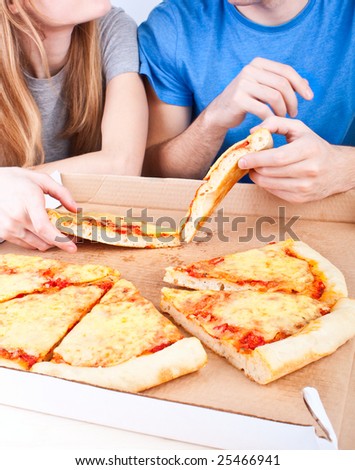 two young people eating pizza from a box