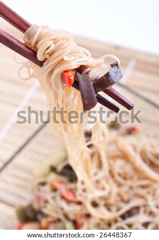 rice noodles with vegetables hanging from chopsticks