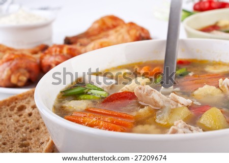 one serving of chicken and vegetable soup with buffalo chicken wings and legs at the back