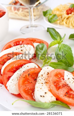 caprese salad and linguine pasta with tomato sauce at the back