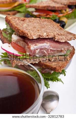 coffee and group of big healthy sandwiches made with whole grain bread, lettuce, vegetables and meat