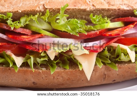 long whole wheat baguette sandwich with meat,vegetables and cheese