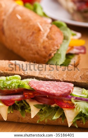 long sub sandwiches with salami on wooden table