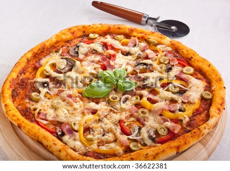 whole bacon and mushroom pizza with a pizza-cutter