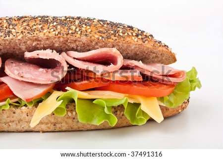 long whole wheat baguette sandwich with lettuce, tomatoes, ham, turkey breast and cheese