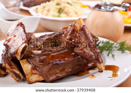 barbecue spare ribs on a plate with vegetables and couscous