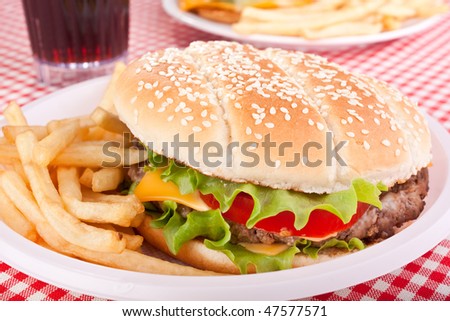 cheeseburger, french fries and cola on a plastic plate
