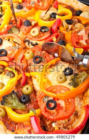 cutting vegetable pizza with a pizza-knife