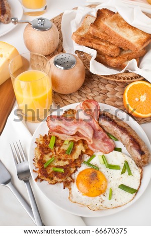 Traditional Manhattan brunch: classic breakfast meal - bacon, egg, sausage and hash browns with toastes and orange juice