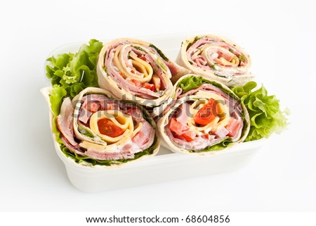 box with wrapped tortilla sandwich rolls stuffed with meat, cheese and vegetables  cut in half on white background