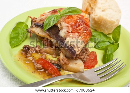 serving of  greek moussaka with eggplants, ground meat, potatoes, tomatoes baked with bechamel sauce and grated cheese